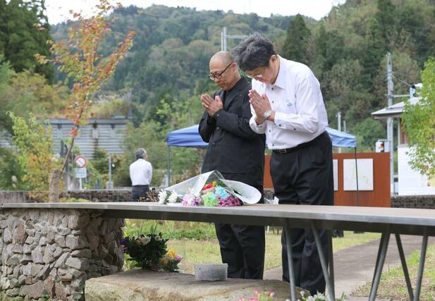 １０月２３日朝、土砂崩れの犠牲者を慰霊するため献花台で手を合わせる人たち＝長岡市妙見町の妙見メモリアルパーク