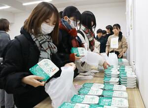 新大コシヒカリのパックご飯を手に取る新潟大学生＝新潟市西区大学南２