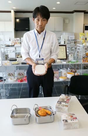 アーネストが売り出した「う米わん」を手にしてPRする高橋俊介さん。手前は「油ターンスクエア」=三条市福島新田
