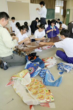 関係者から教わり、こいのぼりの口ひも付けをする須田中の生徒ら=加茂市後須田