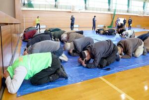 弾道ミサイルが発射された想定で身を守る姿勢を取る住民=11月10日、上越市南城町3