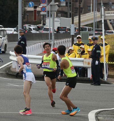 中央学院大の８区黒谷優（左・中越高出）がたすきを渡す＝２０２４年１月３日、横浜市