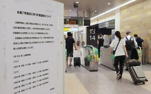 改札口を抜けるUターン客ら。上越新幹線の計画運休を知らせる掲示板がそばに置かれた=16日、新潟市中央区のJR新潟駅