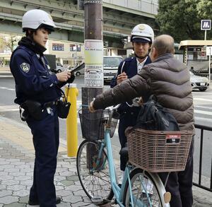 自転車の利用者に注意を呼びかける大阪府警の警察官=11月、大阪市平野区