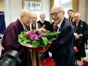 講演後、清水寺の森清範貫主(左)から花束を受け取る被団協の田中熙巳代表委員=20日午後、京都市東山区
