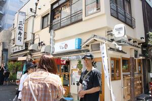 ファンに囲まれるオーナーの難波章浩さん(右)。記念撮影にも気軽に応じる=東京都台東区浅草1の「なみ福 浅草店」