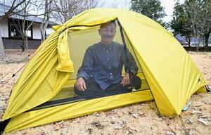 　自社のテントに座るヘリテイジの佐藤信吾社長。「メッシュ生地の軽いテントはロングトレイルを歩く時も役に立ちます」と話す＝長野県安曇野市