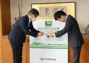 リサイクル材を使った白線用製品の目録を手渡す積水ハウス新潟支店の小坂健支店長(左)=三条市役所