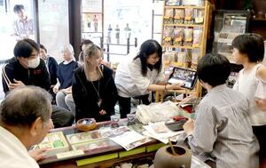 自分たちで手がけたポスターを持参し、店主らと交流する明鏡高校夜間部の生徒たち＝新潟市中央区沼垂東４