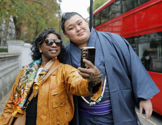 通行人との記念撮影に応じる横綱大の里（右）＝１２日、ロンドン（共同）