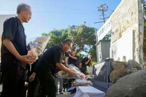 　追悼集会で献花する参列者ら＝２０日午後、沖縄県久米島町