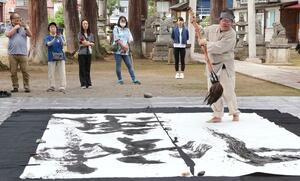 奉納揮毫のパフォーマンスを披露する平野さん=9月23日、十日町市の千手神社