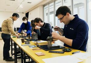 彫金技術を体験する米シェボイガン市のソレンソン市長（手前）ら＝燕市大曲