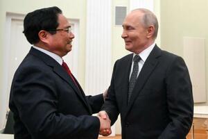 　握手するロシアのプーチン大統領（右）とベトナムのファム・ミン・チン首相＝２５日、モスクワ（タス＝共同）