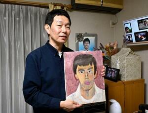 　雪崩事故で亡くなった長男の奥公輝さんが描いた自画像を手にする父勝さん＝１７日午後、栃木県さくら市