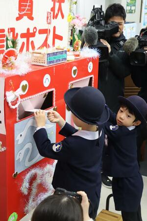 ポストに年賀状を投函する園児たち=16日、新潟市中央区