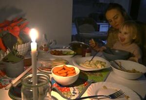 　停電の中でキャンドルをともすマリナ・パークホメンコさん（奥）とアリサちゃん＝２０日、キーウ（共同）