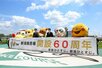 新潟競馬場60周年記念セレモニー 横断幕を持ちゆるキャラたちと記念撮影する風間俊介さん(右から3番目)と新潟競馬場長の杉浦一成さん(左から3番目)=新潟市北区