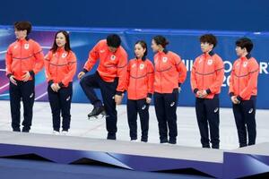 　フィギュアスケート団体の表彰台の前で靴のブレードを気にする木原龍一（左から３人目）＝８日、ミラノ（共同）