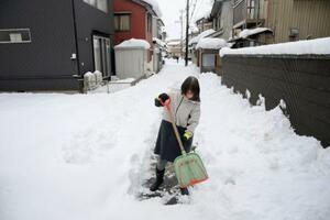 　自宅前で雪かきをする女性＝２５日午後、福井市