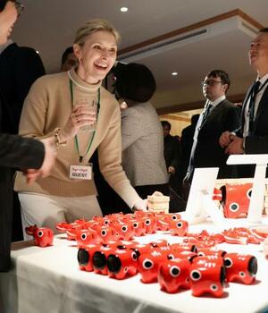 福島県の郷土玩具「赤べこ」を前に笑顔を見せる来場者=21日、スイス東部ダボス(共同)