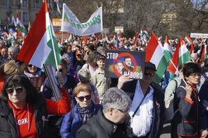 ハンガリーの首都ブダペストで、ウクライナのゼレンスキー大統領らの顔写真と共に「戦争をやめろ」と記したプラカードを掲げて行進するフィデス支持者ら=3月(共同)