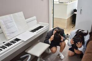 在宅中に避難訓練の防災行政無線が流れ、両手で頭を守る姿勢でかがむ子どもたち=19日午前、石川県輪島市門前町