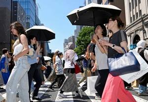 　日傘を差して東京・銀座を歩く人たち。都心は今年初の真夏日となった＝１７日午後