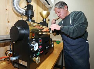 焙煎が終わったばかりのコーヒー豆の香りを確かめる青柳亨さん。「開店まで多くの人に助けてもらった」と感謝する＝魚沼市古新田
