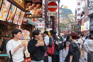 横浜中華街の店先でフライドチキンを食べる男性=17日、横浜市