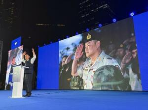 選挙集会で演説するアヌティン首相。背後の大画面に軍服姿が映し出された＝１月、バンコク（共同）