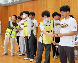新潟産業大付属高校の生徒にドローンの操作方法を教わるマレーシアの水球チームのメンバー=6月3日、柏崎市安田
