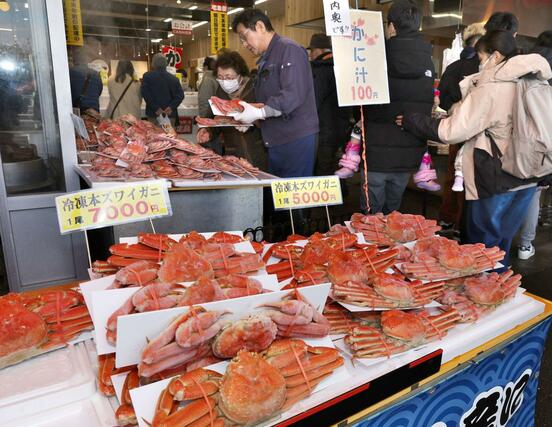 店頭に並んだカニを品定めする買い物客=12月30日、長岡市寺泊下荒町の「市場通り 金八」
