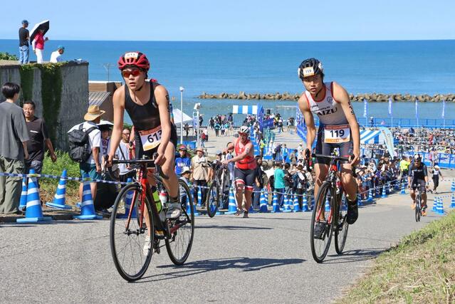 バイクで坂道を駆け抜ける選手たち＝村上市瀬波温泉１