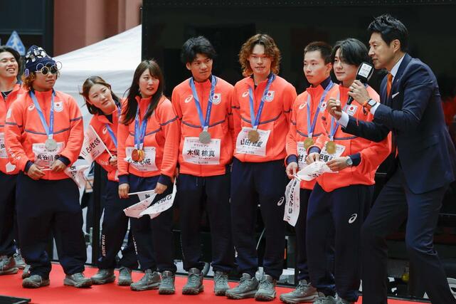 「応援感謝パレード」で、ゲストの松岡修造さん（右端）のインタビューに応じるスノーボードの（右２人目から）戸塚優斗、木村葵来、山田琉聖、木俣椋真、村瀬心椛、小野光希、長谷川帝勝＝２５日午前、東京・日本橋