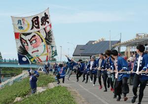 強風の中、巨大な凧を必死に揚げる白根大凧合戦の参加者＝４日、新潟市南区
