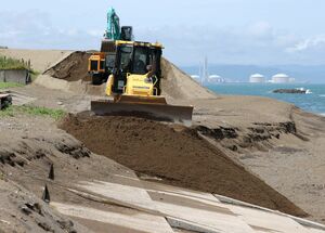 コンクリートが露出した浜に砂を入れる作業が始まった鵜の浜海水浴場=6月24日、上越市大潟区