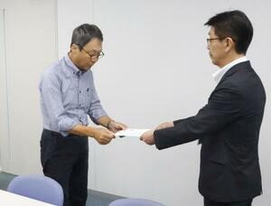 米軍と日本政府に抗議を求める文書を手渡す地元市民団体の久米慶典共同代表(左)=18日午前、山口県岩国市役所