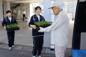 育てたマリーゴールドの苗を地元住民に手渡す岡方中の生徒たち=新潟市北区太子堂
