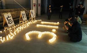 キャンドルを並べ、二つの地震の犠牲者を悼む参列者＝十日町市本町２