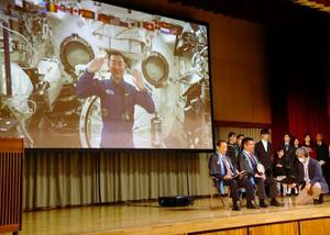 母校の村立川上中で開かれたイベントで、宇宙から村民らと交信する油井亀美也さん(画面)=17日夜、長野県川上村