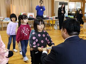 空き缶や古着の売却益で購入した本やおもちゃを園児に手渡した贈呈式＝燕市中島