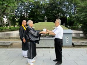 　原爆供養塔の前で、原爆死没者の遺骨を引き渡す教蓮寺の住職ら＝２８日、広島市（同市提供）