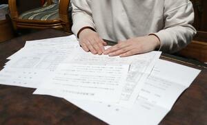 男子生徒の診断書など医療機関の書類を見る母親。被害から4カ月以上を経ても通院が続いている=新潟市