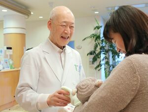 退院する母子にあいさつをする石黒隆雄院長。診察の合間に、記念撮影と見送りを欠かさず行う=三条市