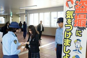 女子高校生に盗撮に注意するよう呼びかける新潟署員=JR新潟駅
