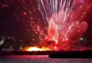 横浜市で開かれていた花火大会で、炎上する海上の台船から打ち上がる花火=4日