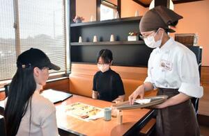　飲食店で接客するタンダラインさん＝１４日、鹿児島県いちき串木野市