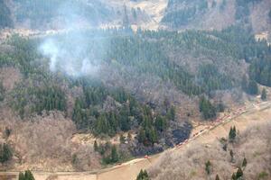 燃え広がって煙を上げる山林。消防防災ヘリが出動し鎮火した＝４月８日、長岡市小国町小栗山（本社ヘリから）