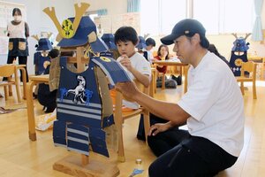 よろいかぶとにシールを貼り付ける園児と保護者ら=阿賀野市学校町